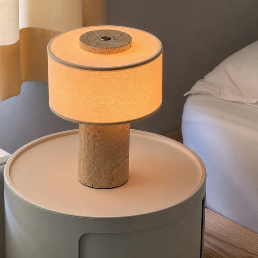 A modern table lamp with textured stone base and fabric drum shade