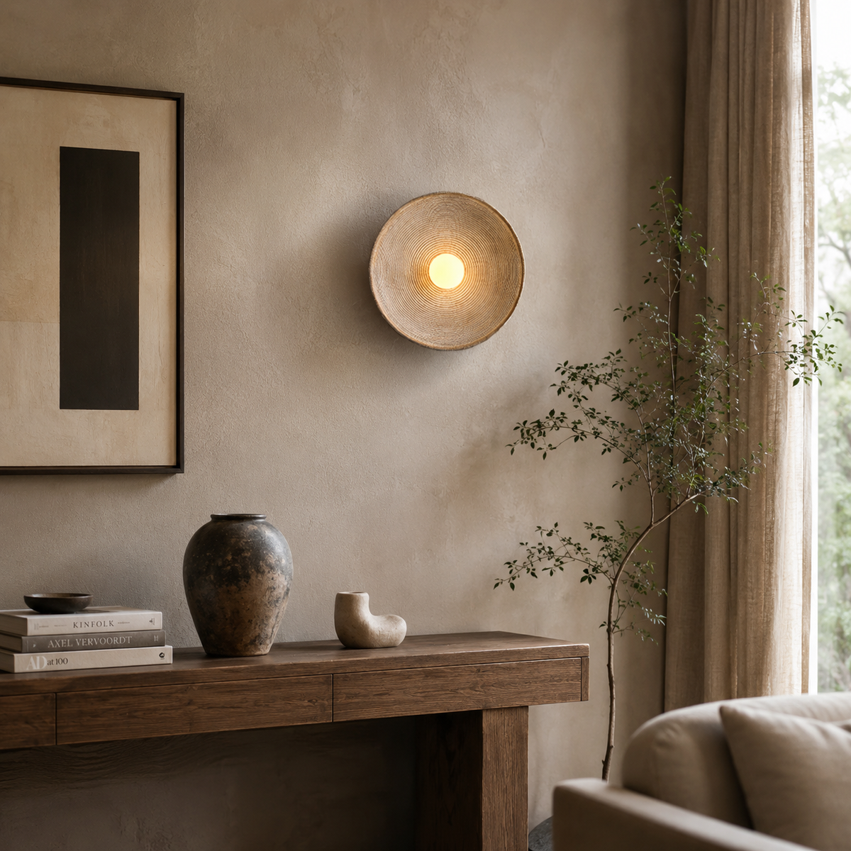 A round, shallow bowl-shaped wall sconce with a textured beige metal rim