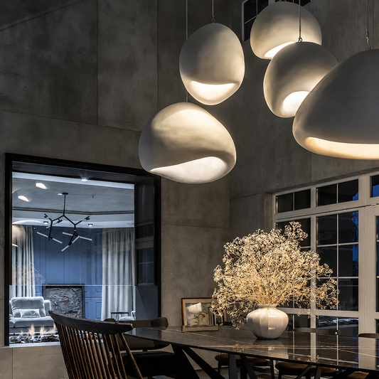 A dining room interior with several large, organic-shaped pendant lights glowing above a table