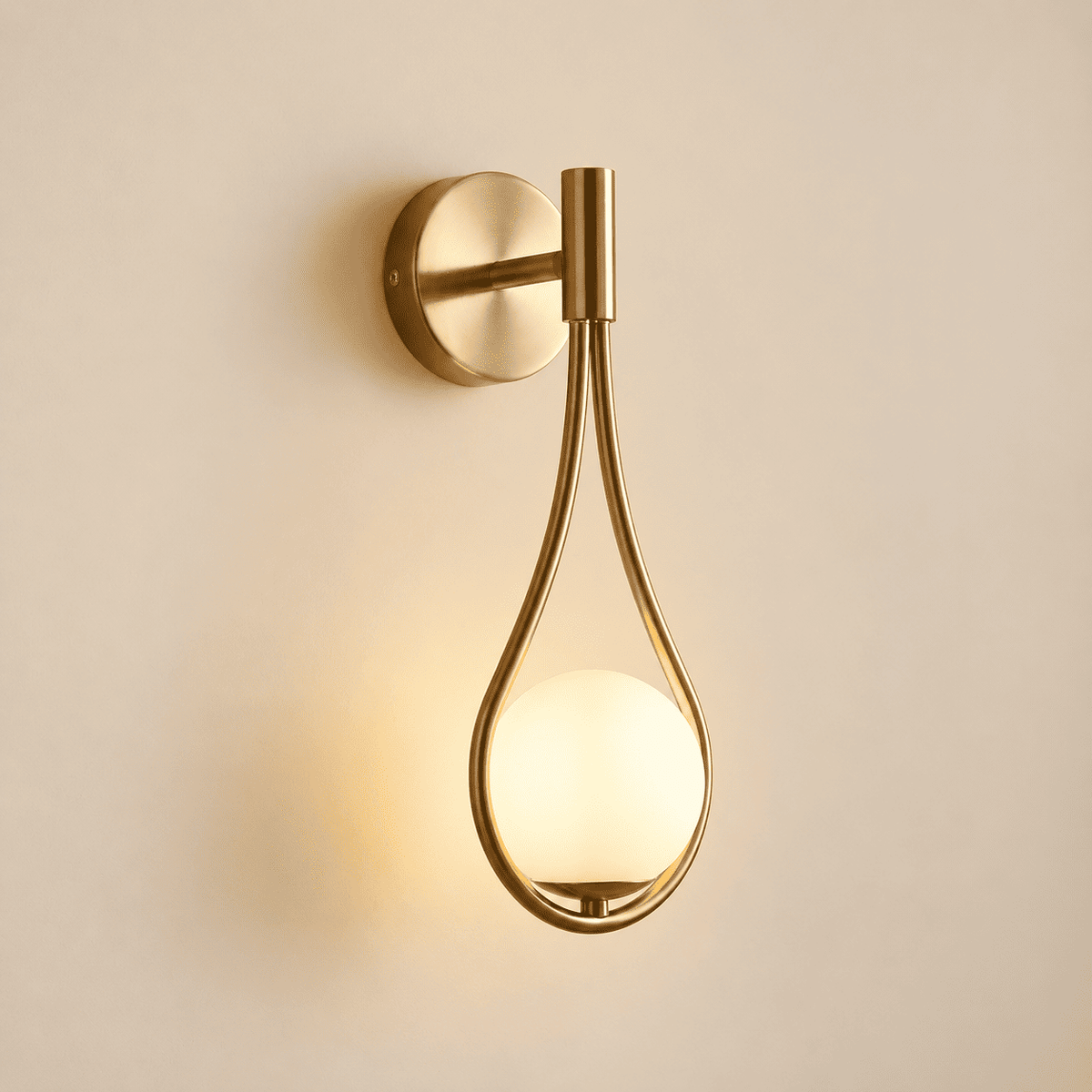 A modern wall-mounted sconce with a brushed gold metal frame and a glowing frosted glass globe