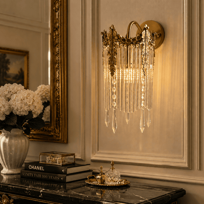 Wall sconce with hanging clear crystal prisms, mounted on a beige paneled wall