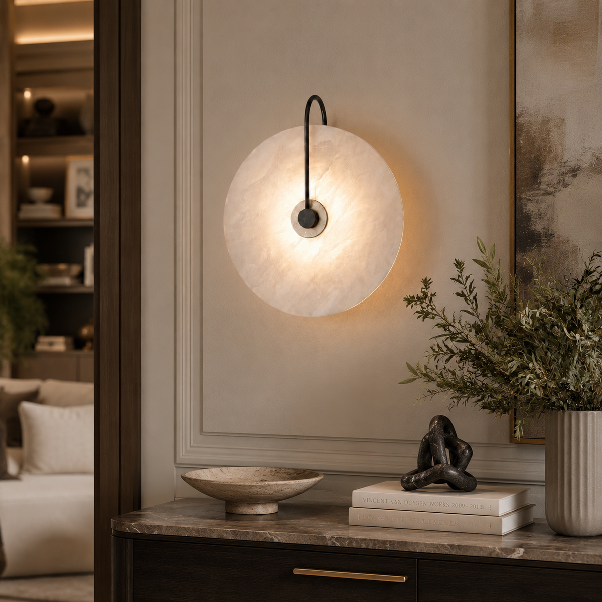 A modern circular wall sconce with a glowing warm white textured disc and a black curved arm