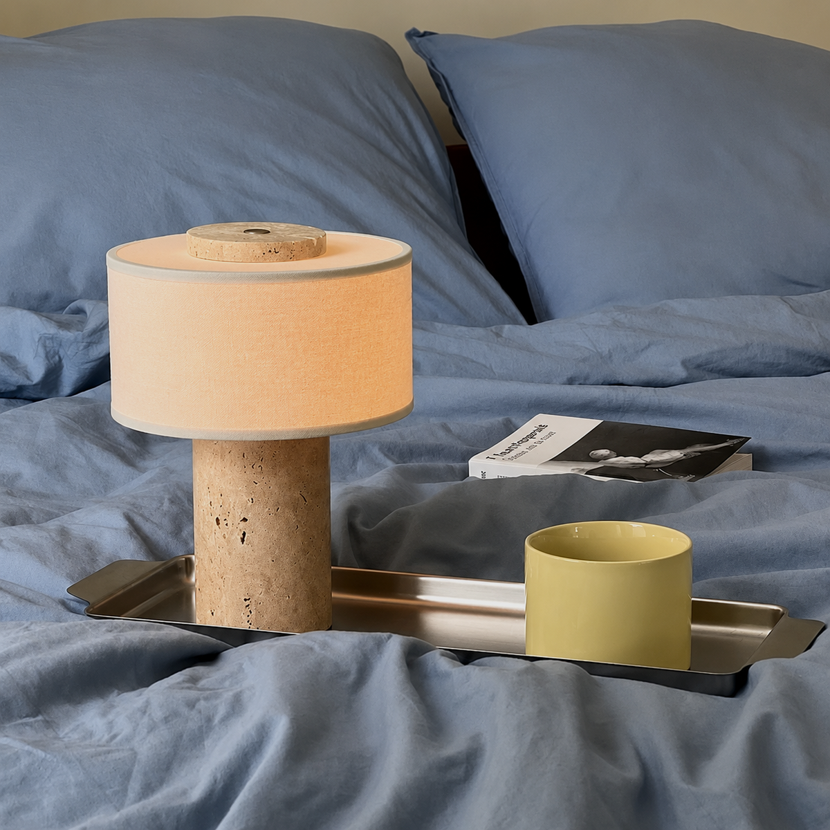 A modern table lamp with a cylindrical cork base and fabric drum shade