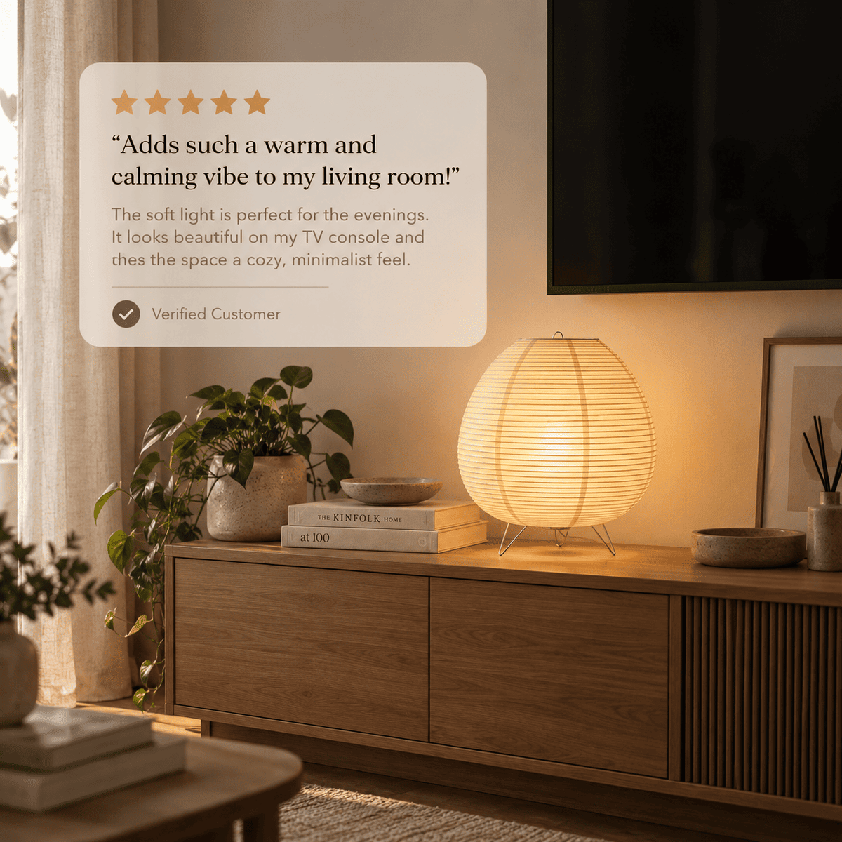 A paper lantern table lamp sits on a wooden console table