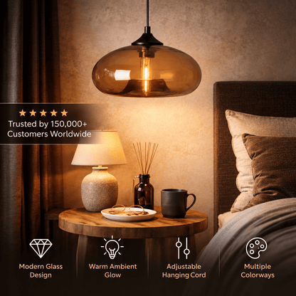 A modern pendant light with a warm amber-tinted glass dome and black metal hardware