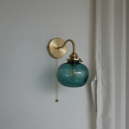 Wall-mounted lamp with blue glass shade and brass fixture on a plain wall