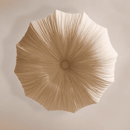 A top-down view of a pleated, mushroom-shaped pendant light in a warm beige fabric