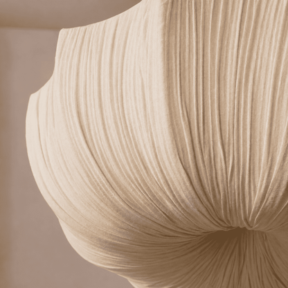 A close-up of a beige pleated fabric or textile draped in soft