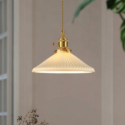 Pendant light with a ribbed glass shade against a neutral wall.