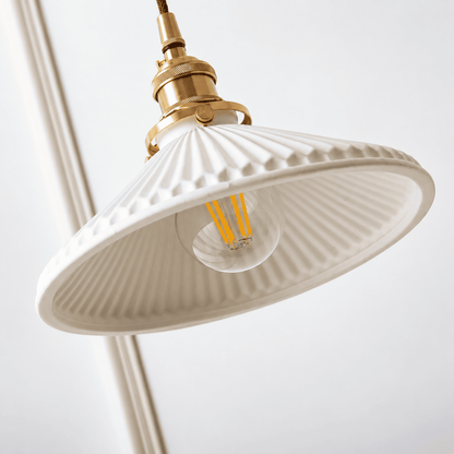 A close-up of a hanging pendant light with a white ribbed glass shade, a brass metal fixture