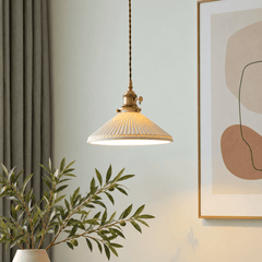 A single pendant light with a ribbed cream glass shade and brass-toned metal fixture hanging in a styled interior.