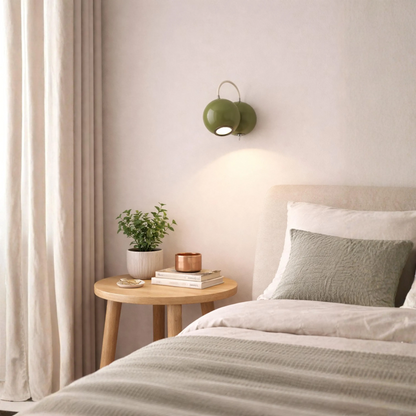 A green wall-mounted sconce with two round shades and a curved arm